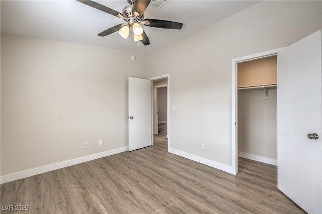 unfurnished bedroom with a ceiling fan, visible vents, wood finished floors, baseboards, and a closet