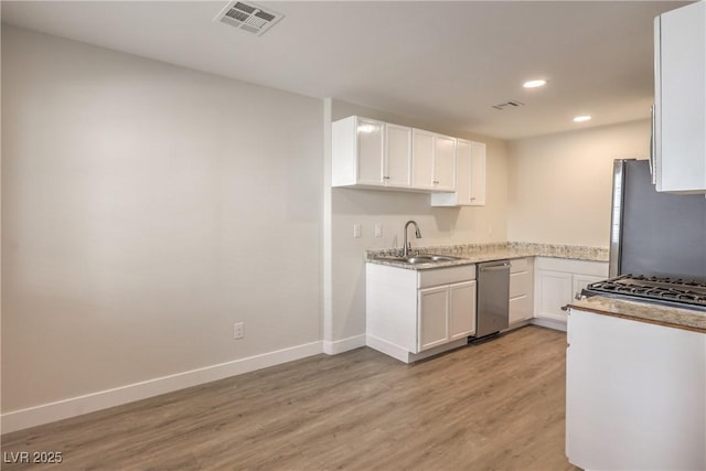 kitchen with a sink, light wood-style flooring, stainless steel appliances, baseboards, and visible vents