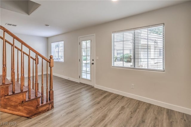 foyer entrance with baseboards, stairs, wood finished floors, and visible vents