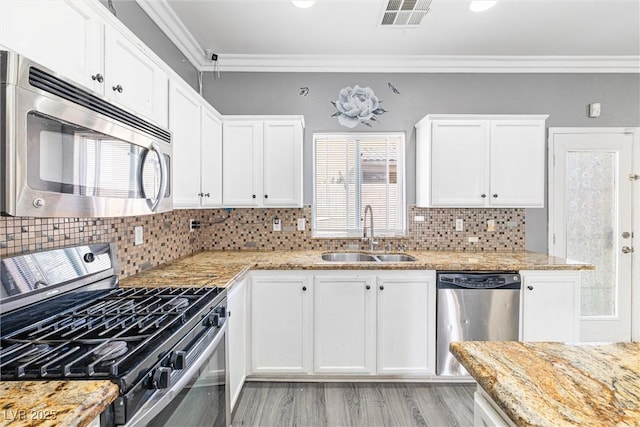 kitchen featuring visible vents, crown molding, a sink, stainless steel appliances, and white cabinetry