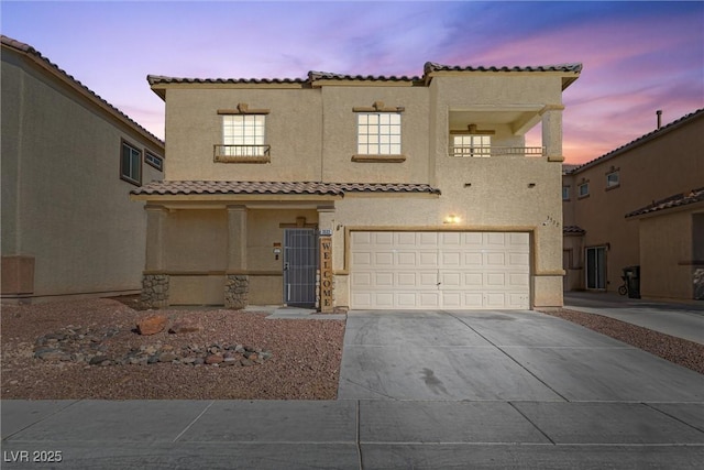 mediterranean / spanish home featuring a tiled roof, a garage, driveway, and stucco siding