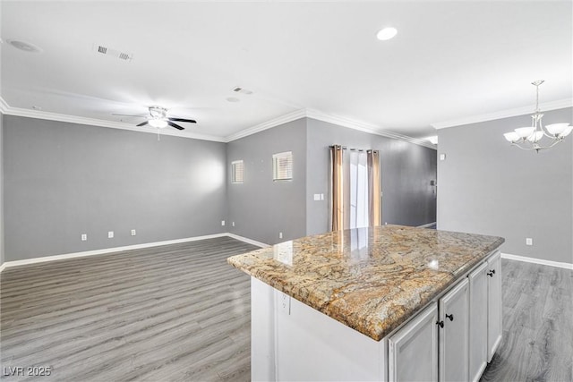 kitchen featuring a kitchen island, visible vents, ceiling fan with notable chandelier, light wood finished floors, and ornamental molding