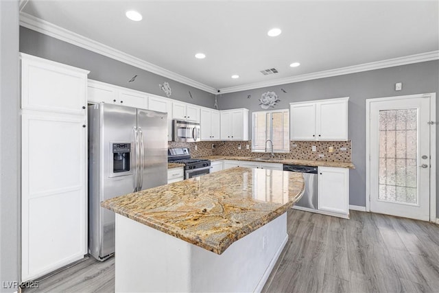 kitchen featuring stainless steel appliances, white cabinetry, light wood-type flooring, visible vents, and ornamental molding