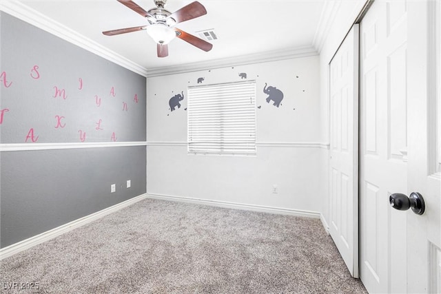 carpeted spare room with ceiling fan, visible vents, ornamental molding, and baseboards