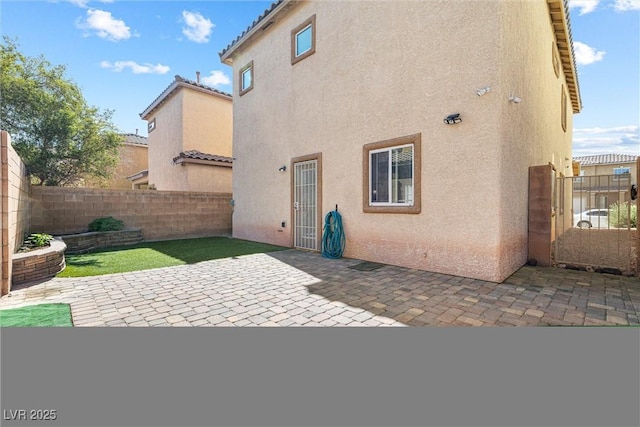 back of property with a fenced backyard, a patio area, and stucco siding