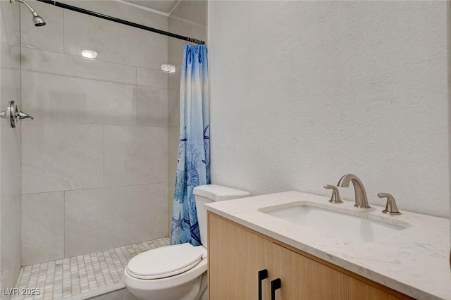 full bathroom with toilet, a textured wall, a tile shower, and vanity
