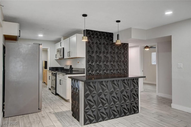 kitchen with dark countertops, baseboards, white cabinetry, hanging light fixtures, and stainless steel appliances