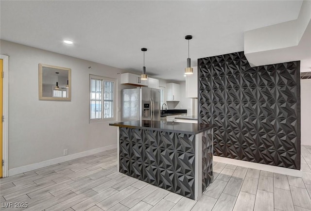 kitchen with dark countertops, wood finish floors, stainless steel refrigerator with ice dispenser, and white cabinetry