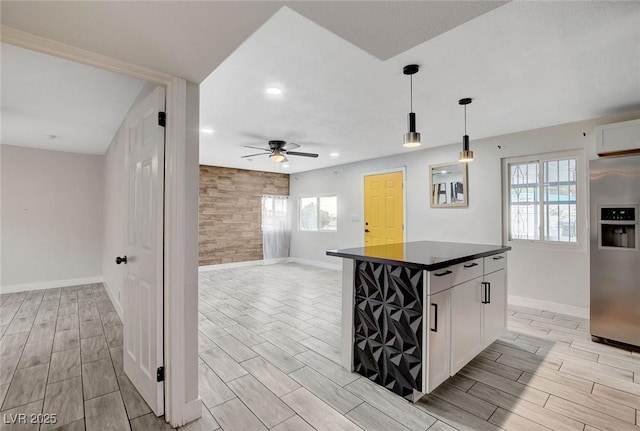 kitchen with baseboards, wood finish floors, dark countertops, and stainless steel fridge with ice dispenser