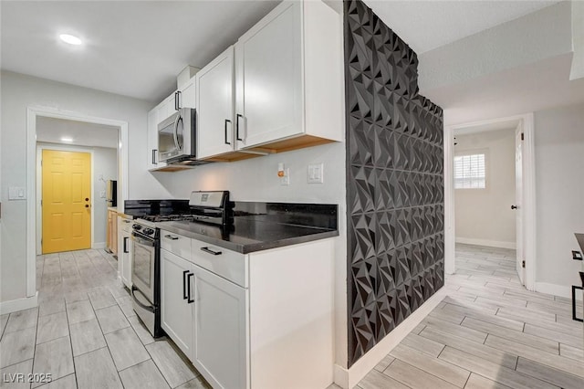 kitchen with dark countertops, baseboards, stainless steel appliances, and wood finish floors