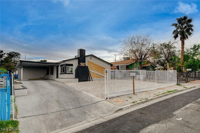 view of front of property with a fenced front yard, stucco siding, driveway, and an attached carport