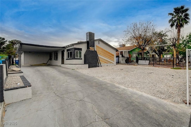 contemporary house with fence, a carport, stucco siding, and concrete driveway