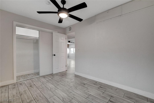 unfurnished bedroom featuring visible vents, a closet, baseboards, wood tiled floor, and ceiling fan