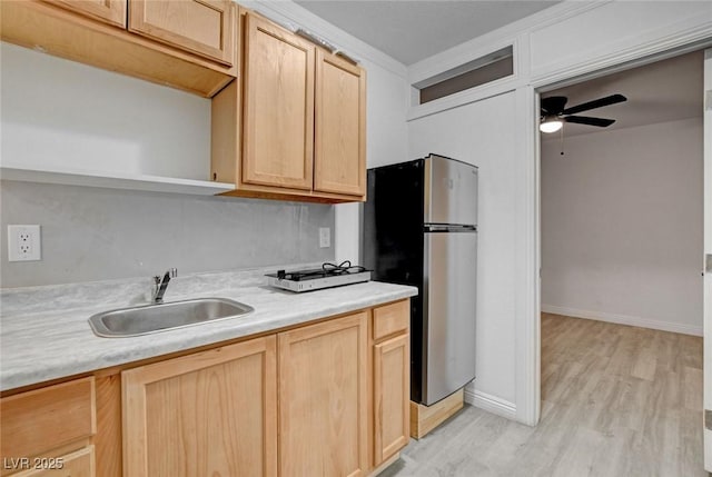 kitchen with a sink, light brown cabinets, open shelves, and freestanding refrigerator