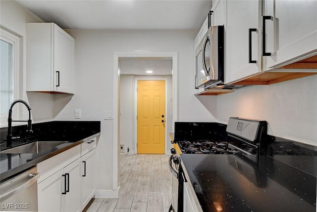 kitchen featuring a sink, white cabinets, stainless steel appliances, and light wood finished floors