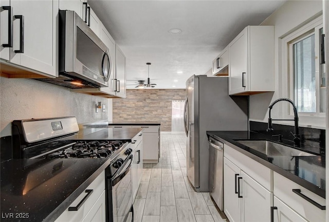 kitchen featuring a sink, ceiling fan, stainless steel appliances, and white cabinetry