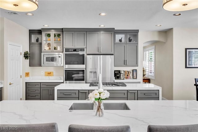 kitchen with arched walkways, appliances with stainless steel finishes, gray cabinets, and recessed lighting