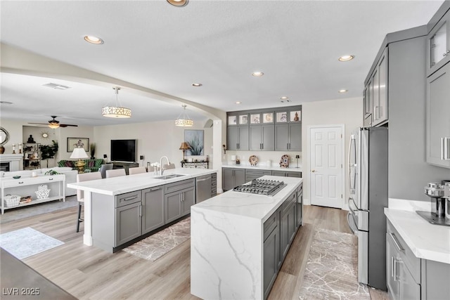 kitchen with a center island, a sink, gray cabinets, and appliances with stainless steel finishes