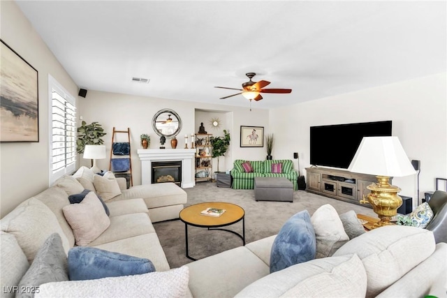 carpeted living room featuring a glass covered fireplace, ceiling fan, and visible vents