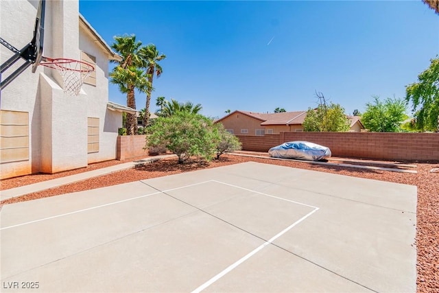 view of basketball court with basketball hoop and a fenced backyard