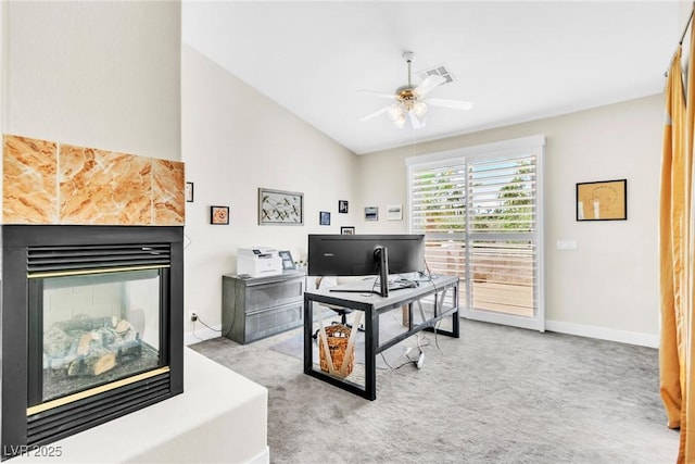 office area featuring baseboards, ceiling fan, carpet flooring, a multi sided fireplace, and vaulted ceiling