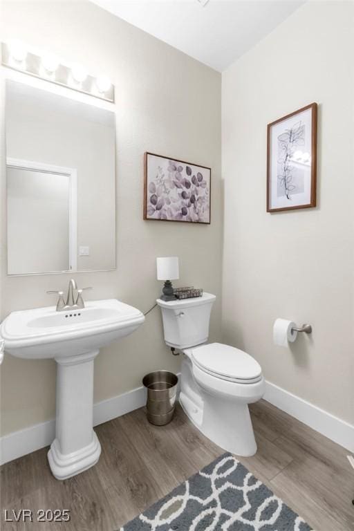 bathroom with baseboards, toilet, and wood finished floors