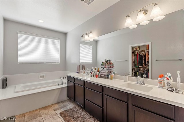 full bathroom with a walk in closet, a sink, double vanity, visible vents, and a garden tub