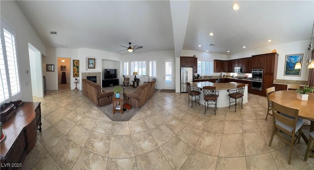 living room featuring ceiling fan, visible vents, a fireplace, lofted ceiling, and recessed lighting