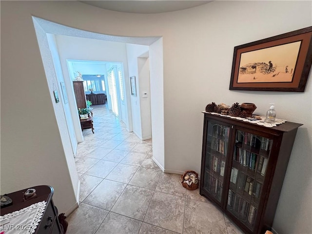 hallway with light tile patterned floors and baseboards