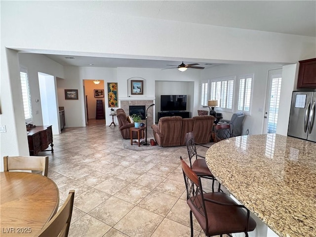 living area featuring a tiled fireplace and ceiling fan