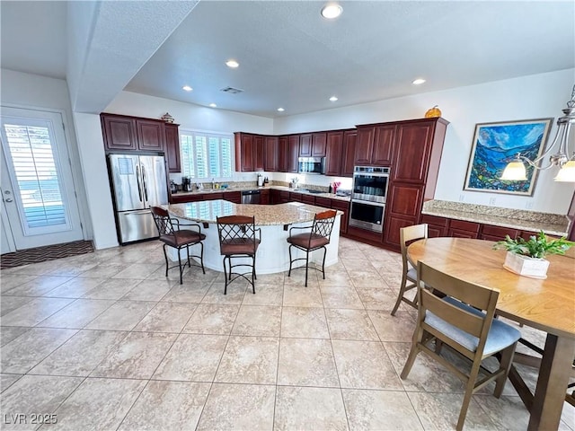 kitchen featuring light stone countertops, appliances with stainless steel finishes, a kitchen breakfast bar, a center island, and recessed lighting