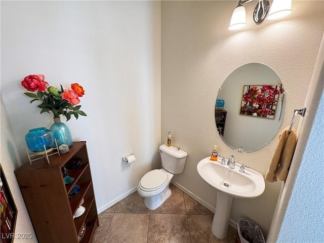 bathroom featuring toilet, baseboards, a sink, and tile patterned flooring