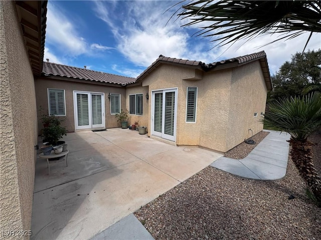 rear view of house featuring a tile roof, a patio area, and stucco siding