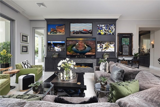tiled living room featuring a glass covered fireplace, ornamental molding, and visible vents