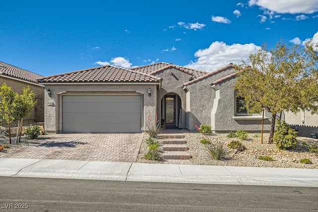 mediterranean / spanish home with an attached garage, stucco siding, driveway, and a tile roof