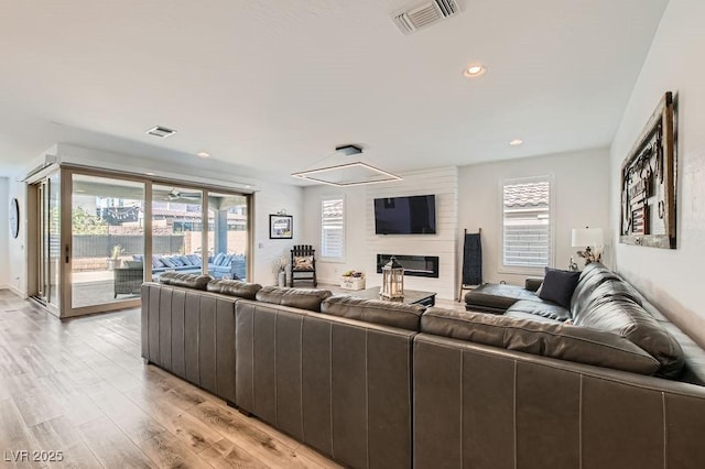 living area with recessed lighting, visible vents, a large fireplace, and light wood-style floors