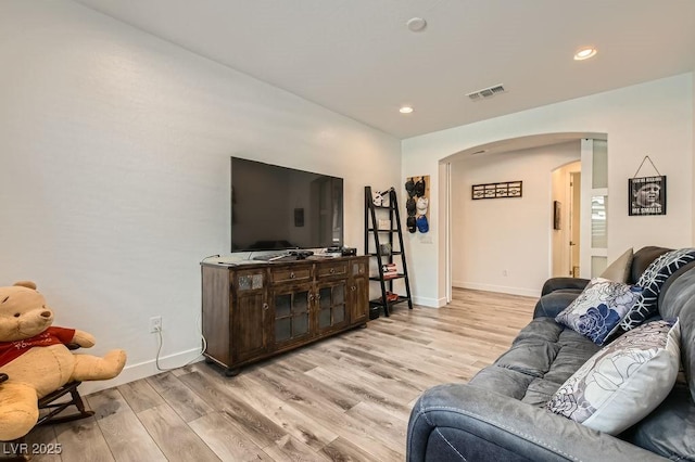 living room with arched walkways, light wood-style flooring, recessed lighting, baseboards, and visible vents