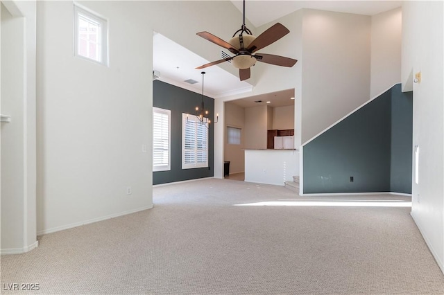 unfurnished living room with carpet floors, visible vents, baseboards, a high ceiling, and ceiling fan with notable chandelier