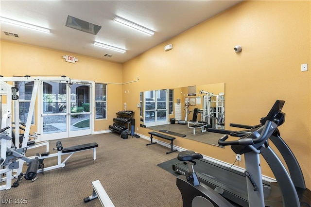 gym featuring high vaulted ceiling, visible vents, baseboards, and carpet