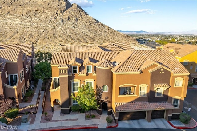 exterior space featuring a garage, a mountain view, stucco siding, and a tiled roof