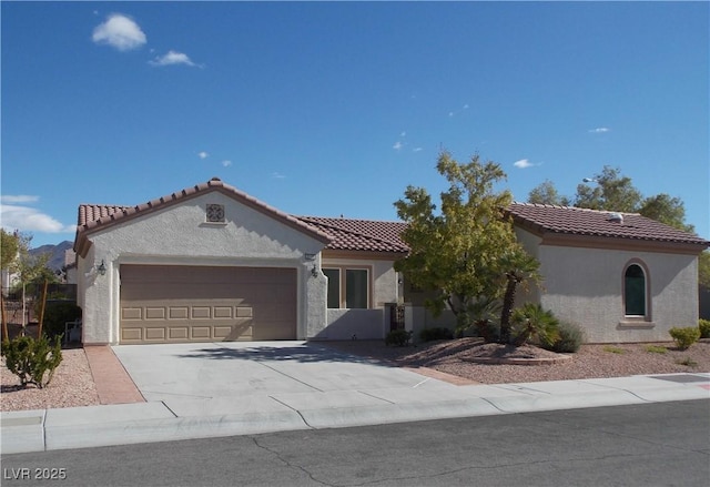 mediterranean / spanish-style home featuring an attached garage, driveway, a tile roof, and stucco siding