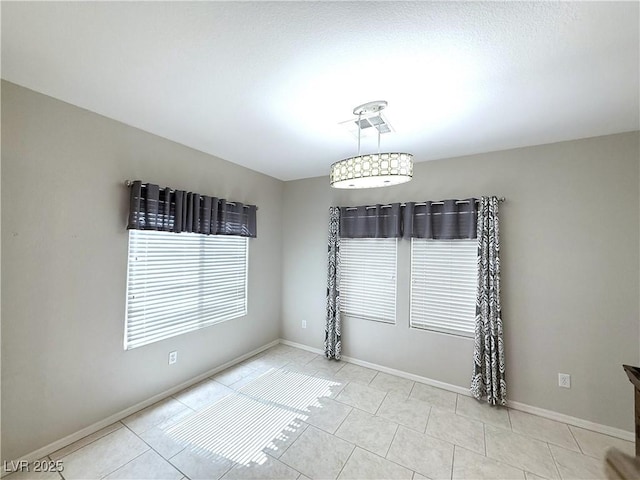 tiled empty room featuring baseboards