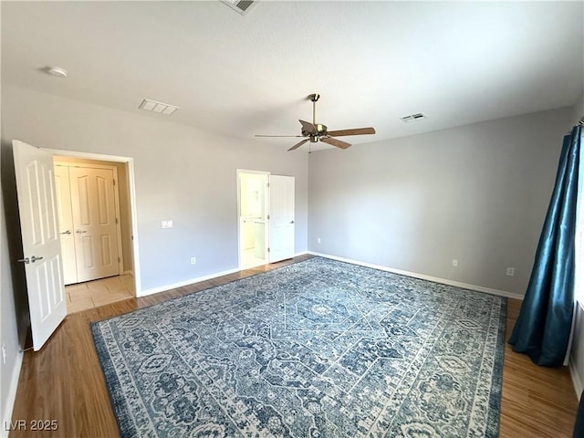 unfurnished bedroom with baseboards, wood finished floors, and visible vents