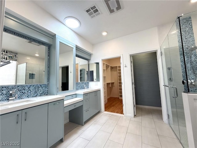 full bathroom with visible vents, decorative backsplash, a sink, and a stall shower