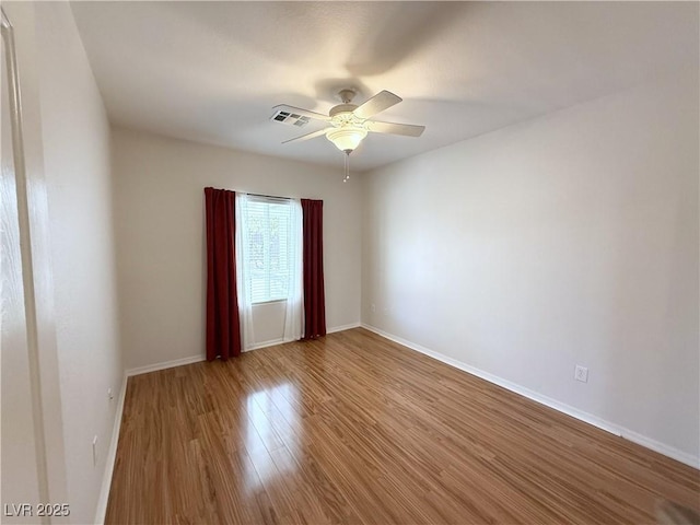 empty room with ceiling fan, baseboards, visible vents, and wood finished floors