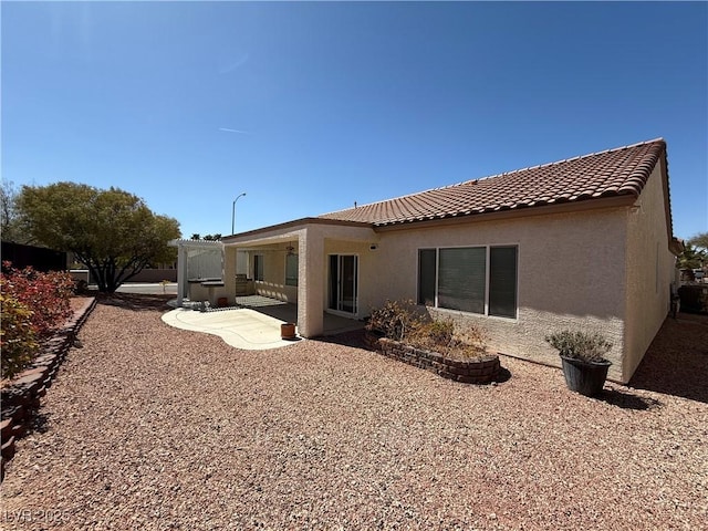 rear view of house featuring a patio area, stucco siding, and a tiled roof