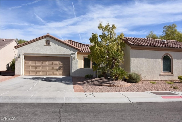 mediterranean / spanish house with a tiled roof, a garage, stucco siding, and driveway