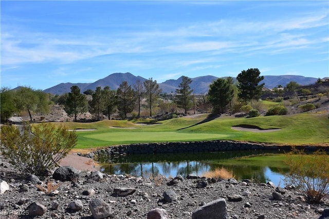 surrounding community with a lawn, golf course view, and a water and mountain view
