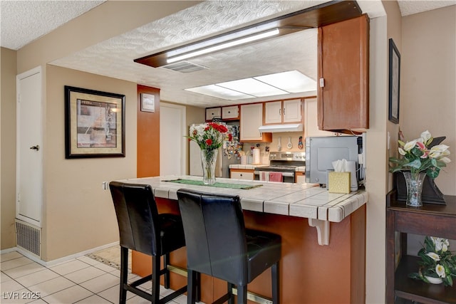 611 Spyglass Ln, Las Vegas, NV 89107 - kitchen with tile counters, stainless steel appliances, a peninsula, and visible vents
