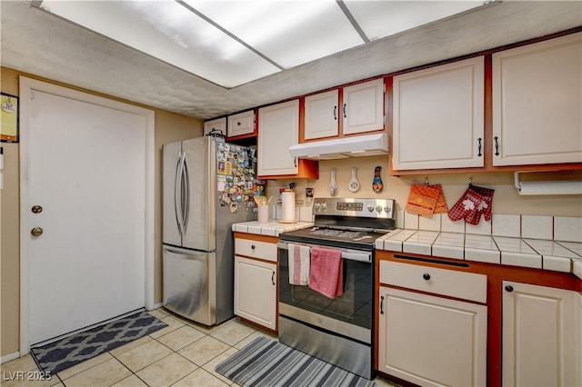 611 Spyglass Ln, Las Vegas, NV 89107 - kitchen featuring tile counters, stainless steel appliances, white cabinetry, light tile patterned floors, and under cabinet range hood